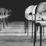 Rows of empty chairs in a quiet, dimly lit room, symbolizing absence, grief, and missing people.